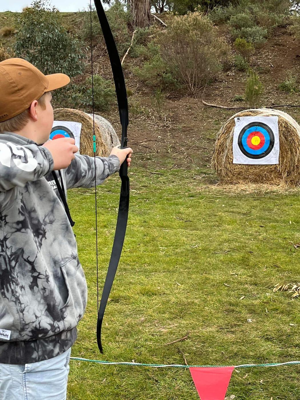 A student drawing back a recurve bow at the archery range