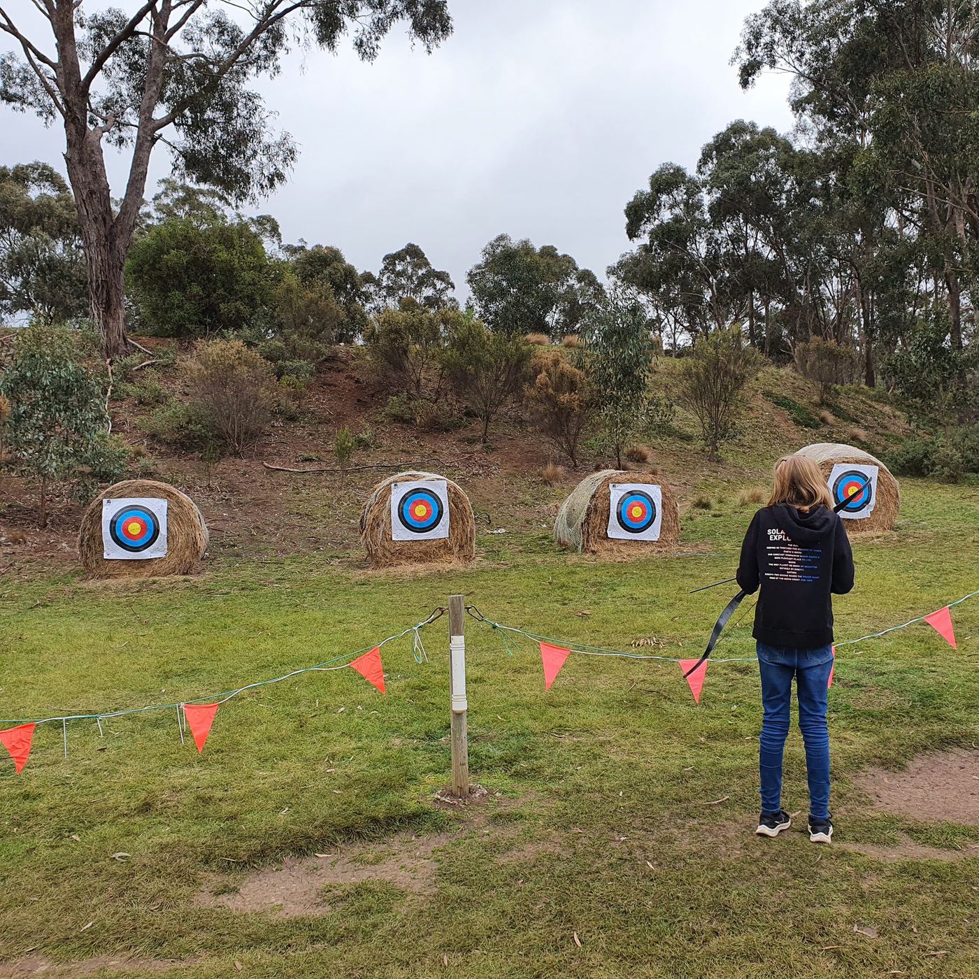 Students at the Sunnystones archery range shooting at round targets set against the hillside