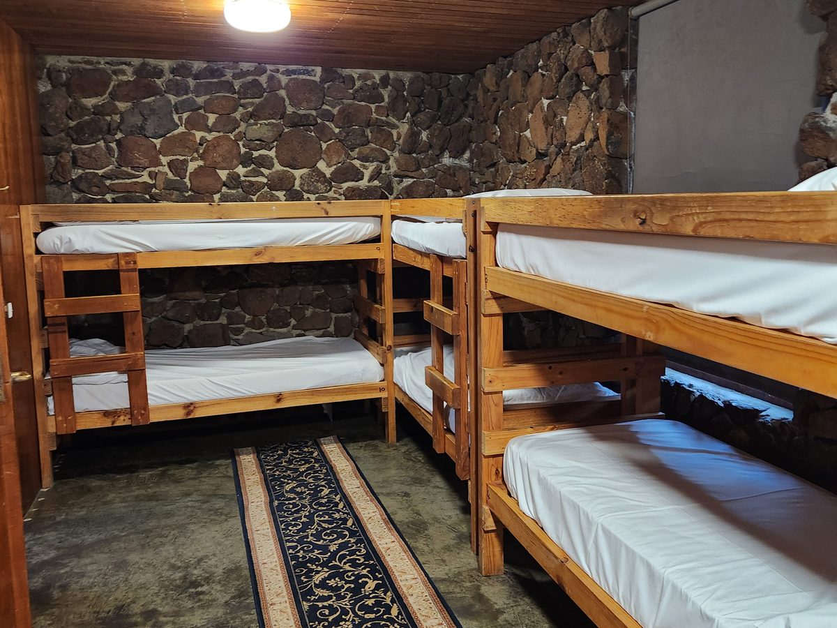 Timber bunk beds made up with white linen in a stone-walled homestead bedroom