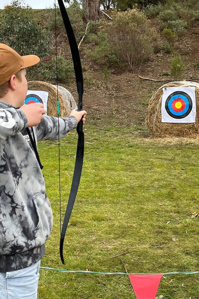 A student drawing back a recurve bow