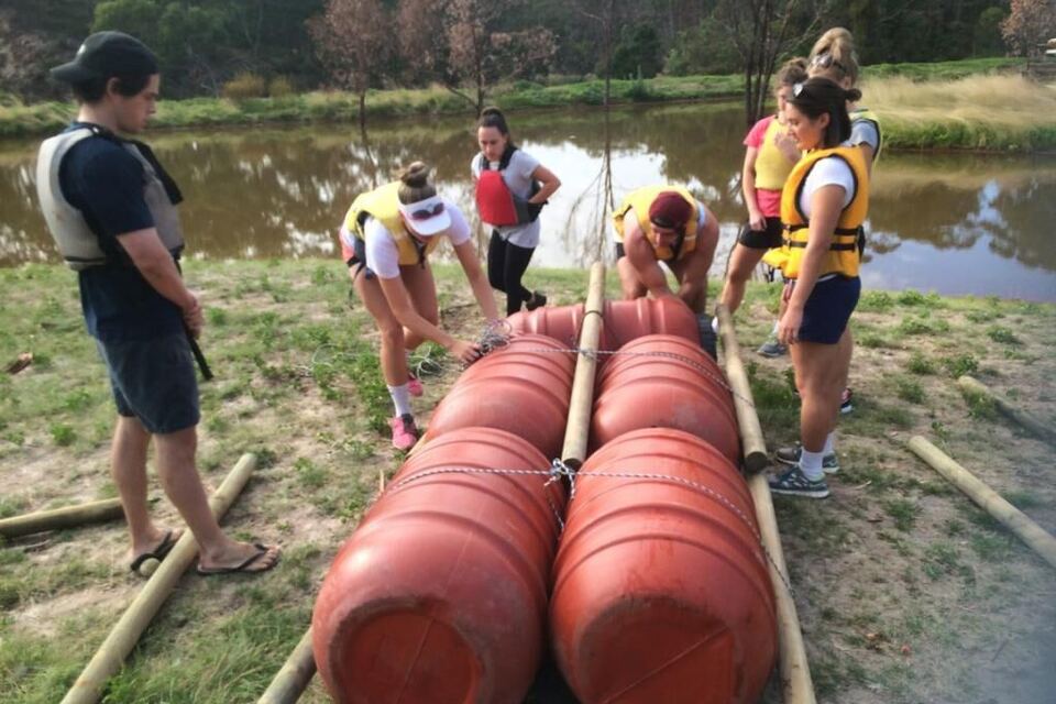 A group lashing barrels and poles together into a raft