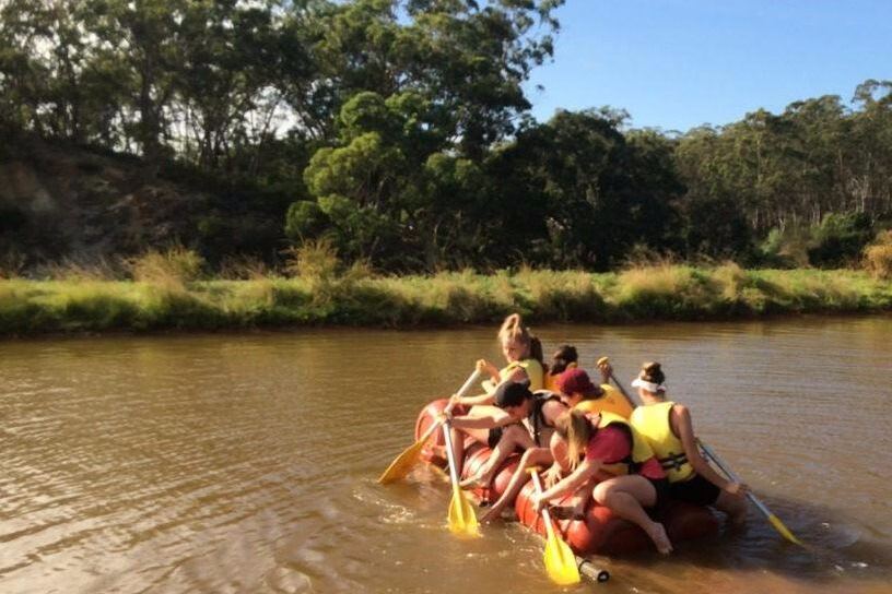 Students paddling their home-built raft on the dam
