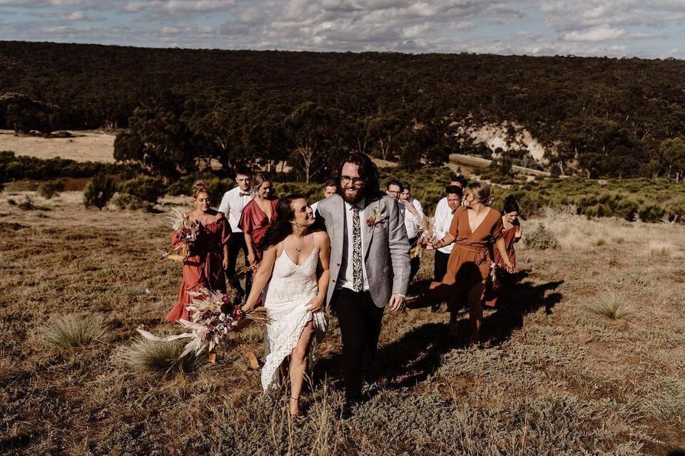 The bridal party walking through the golden paddock