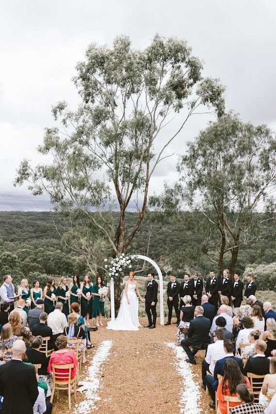 Guests seated for a ceremony under a spreading gum tree