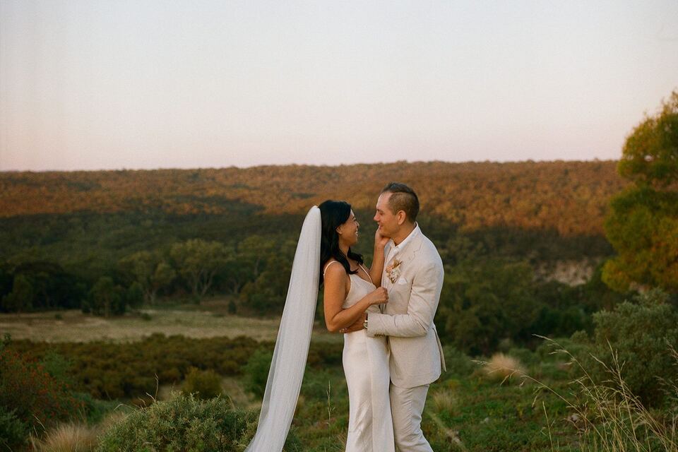 Newlyweds embracing at golden hour above the valley
