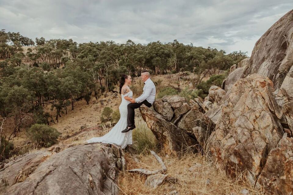 Newlyweds seated on the granite rocks above the bush