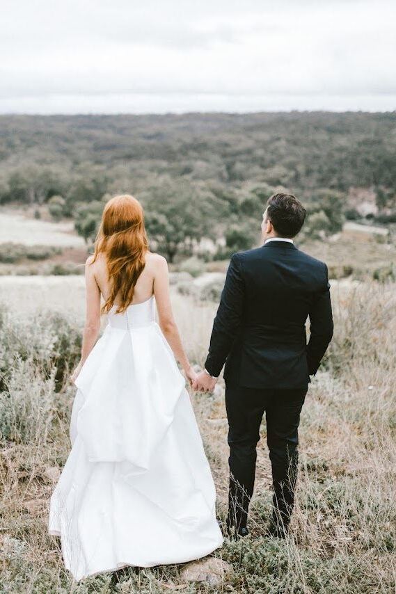 Bride and groom walking hand in hand through the bush