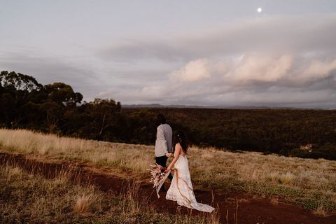 The bride walking alone across the grass at dusk