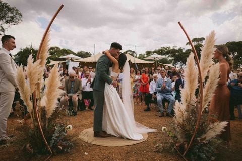 A couple at the altar beneath a pampas grass ceremony arch