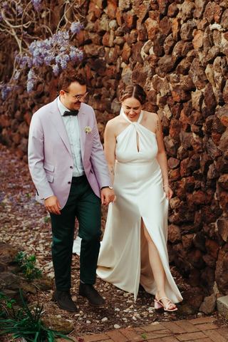 A couple walking together past the stone courtyard wall