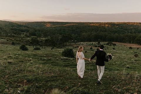 A couple walking away together across the hills at dusk