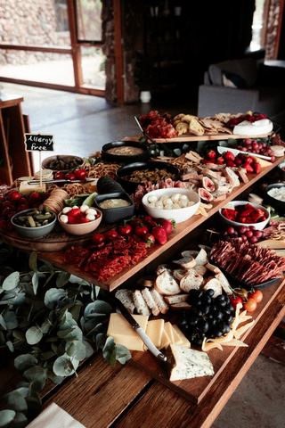 A grazing table piled with fruit, cheese and charcuterie for guests