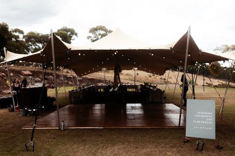 An open-sided marquee set up for the reception on the lawn by day