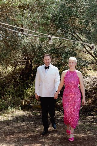 A father walking with the mother of the bride in a bright pink dress