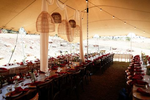A long reception table set under festoon lights inside the marquee at night