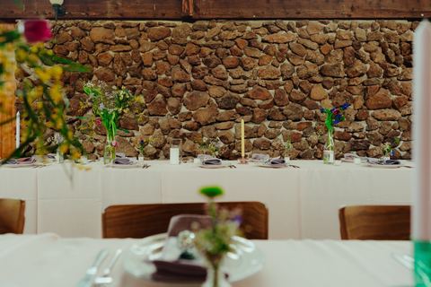 A reception table set for dinner against the homestead's stone wall
