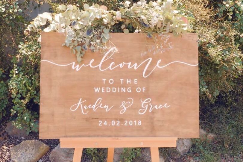 A timber welcome sign dressed with flowers
